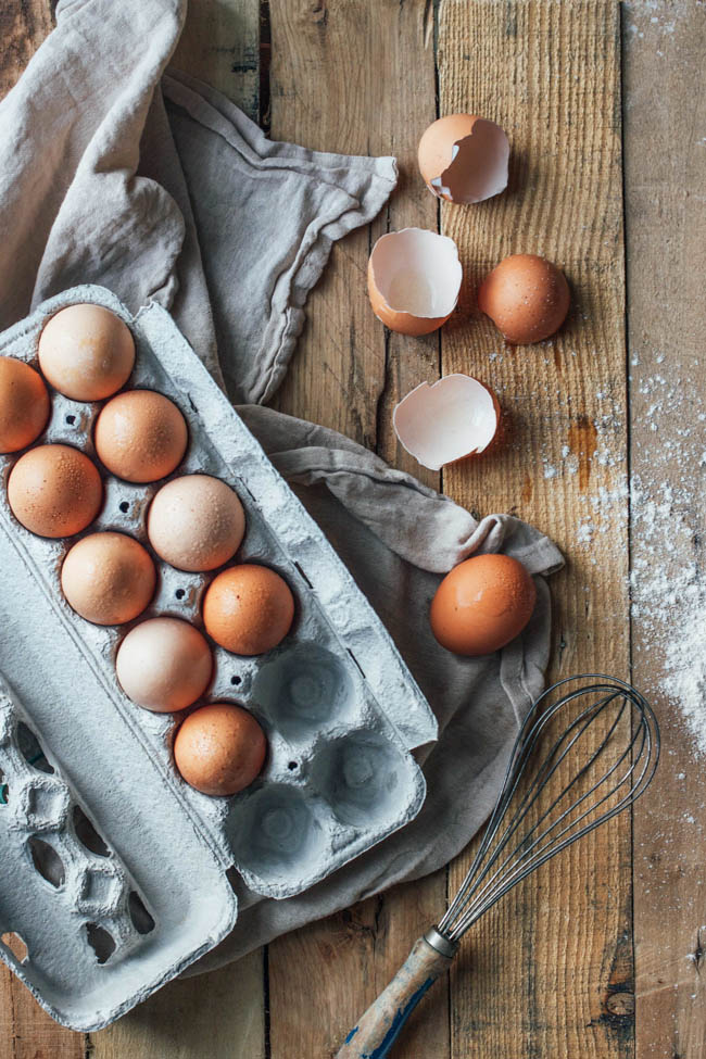 Overhead shot of carton of eggs with a couple of egg shells to the side