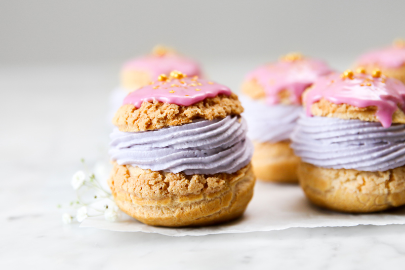 Cream puffed filled with purple cream and topped with pink glaze.