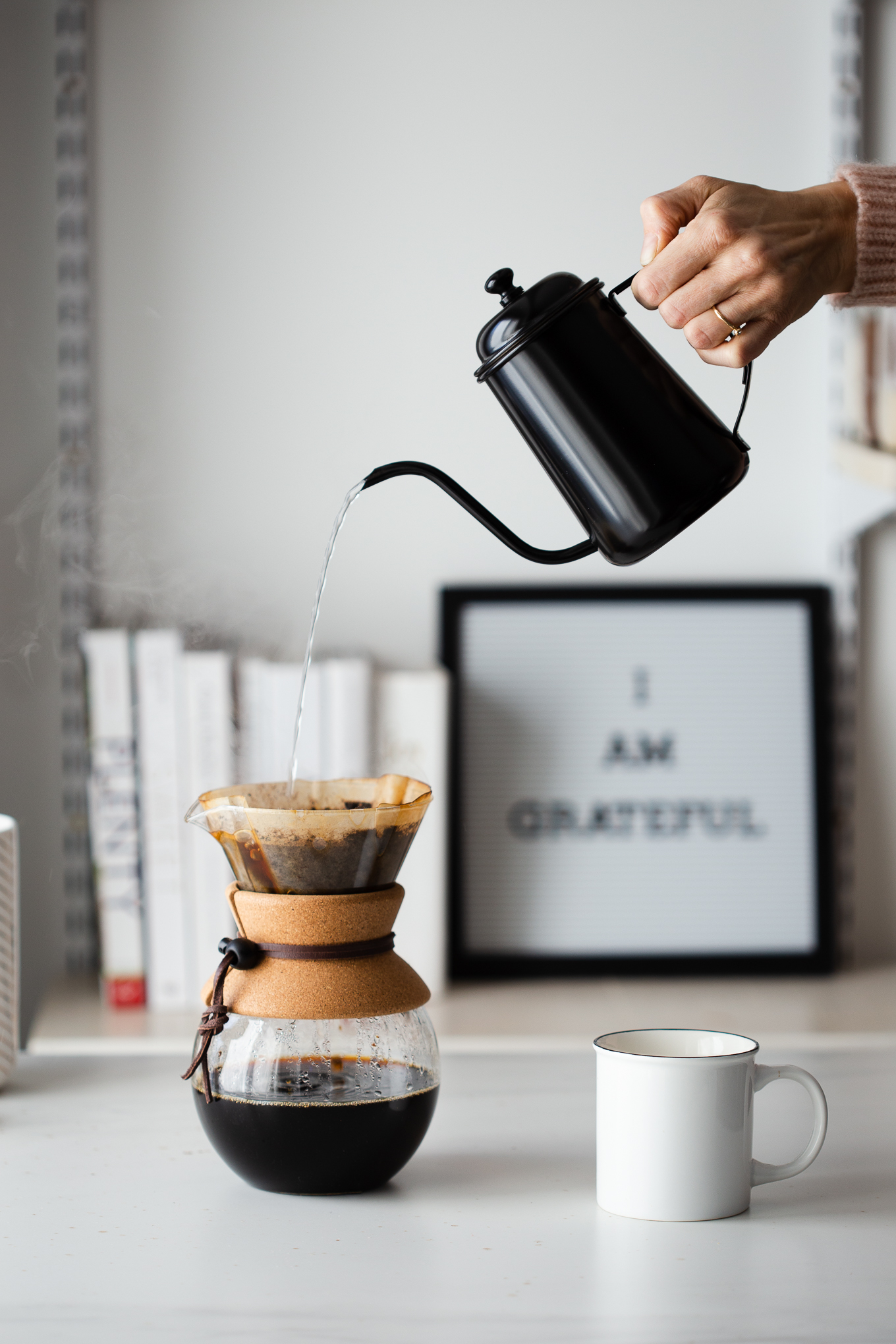 Straight-on shot of water being poured into a pour over coffee maker with a gooseneck coffee drip.
