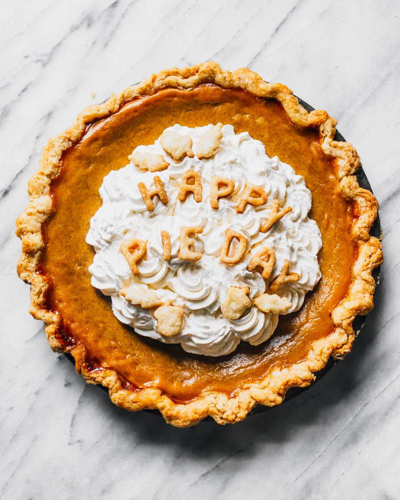 Pumpkin pie with whipped cream topping and pie crust text saying "Happy Pie Day".