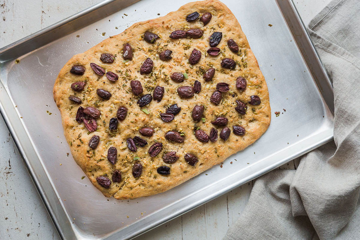 Vegan focaccia topped with olives and rosemary.