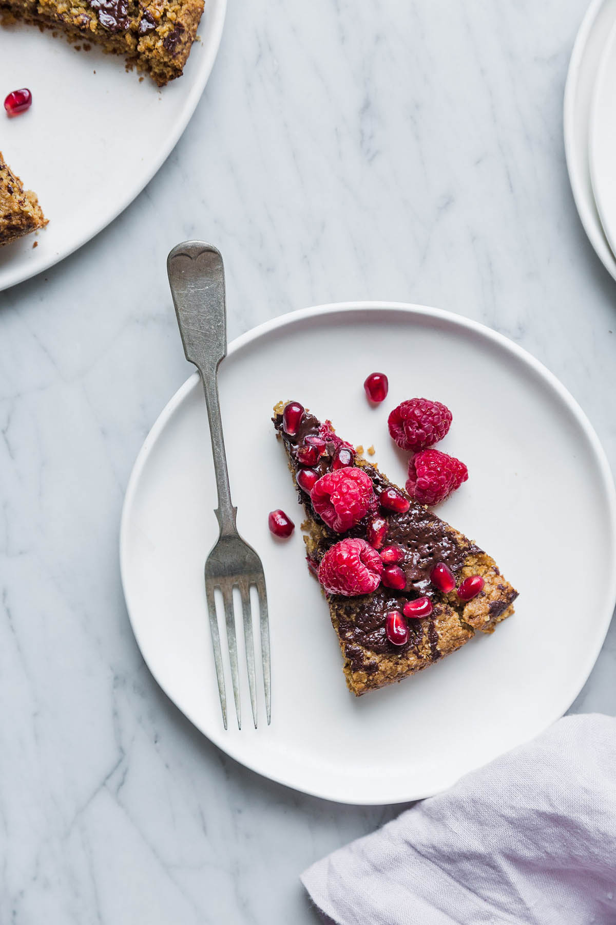 A slice of gluten free almond cake with chocolate chunks and raspberries.