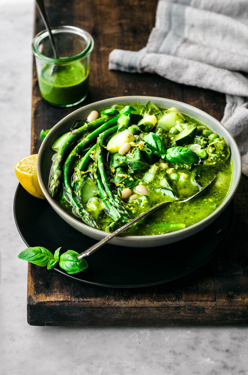 A bowl of green soup with vegetables.