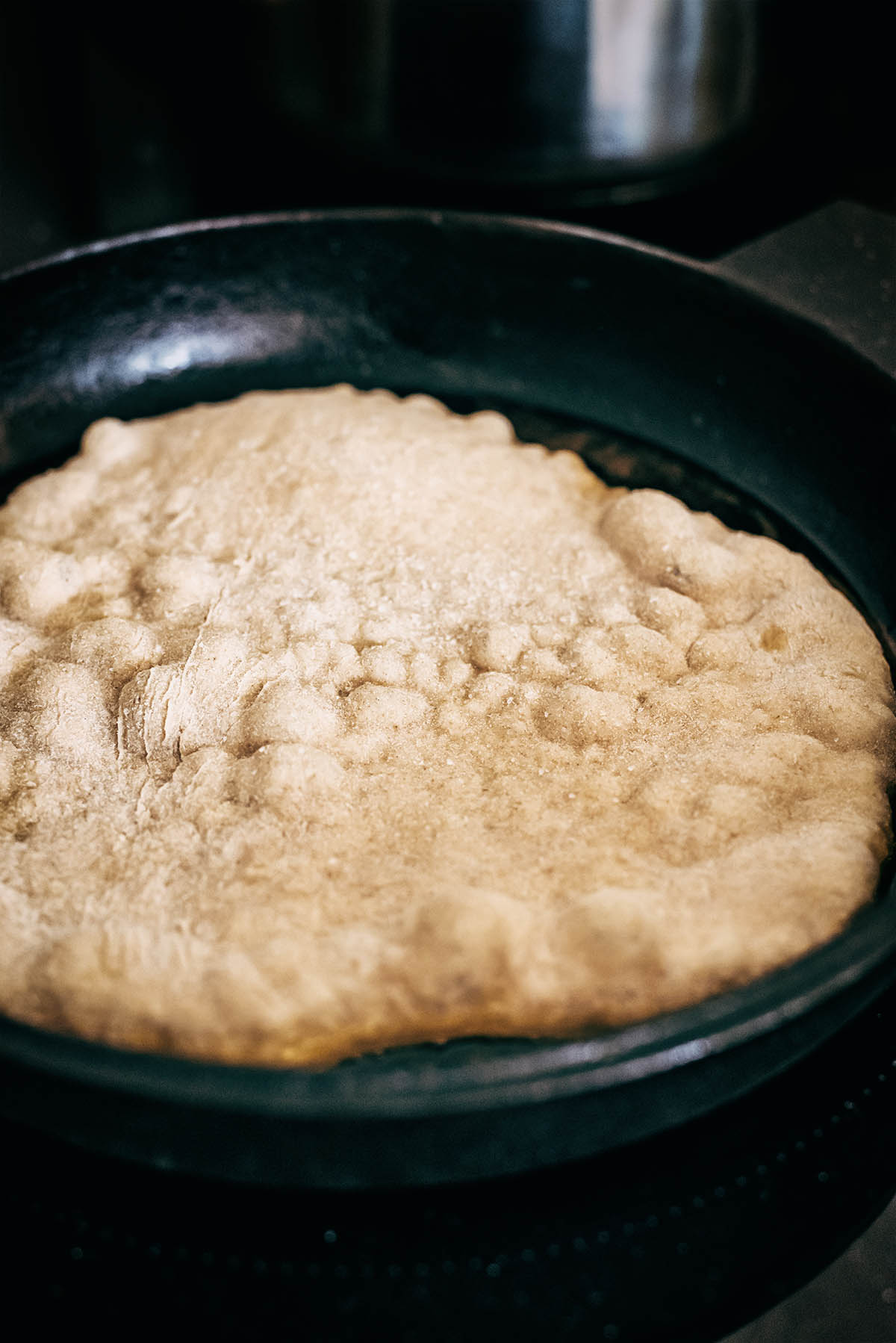 Naan cooking in a cast iron pan.