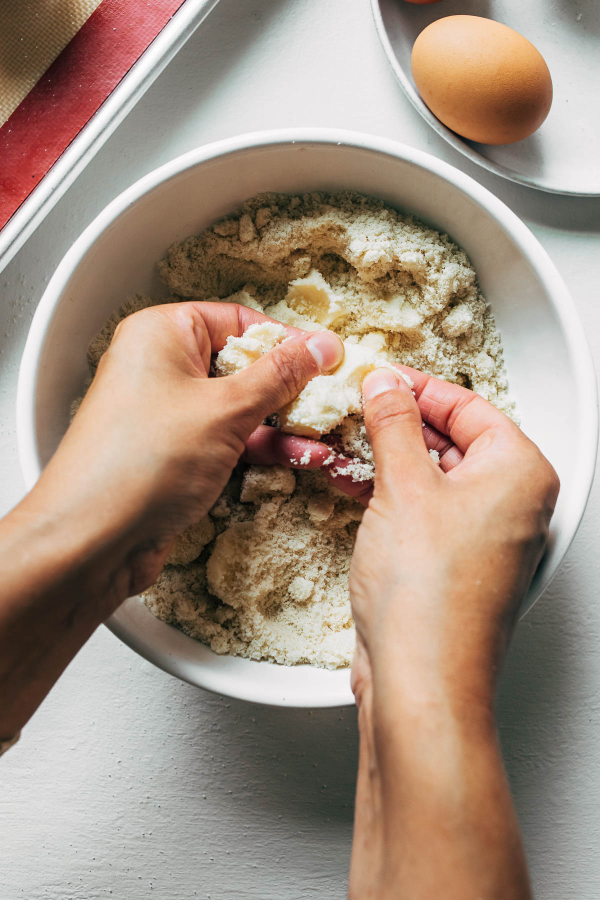Woman's hands mixing butter into an almond flour mixture.