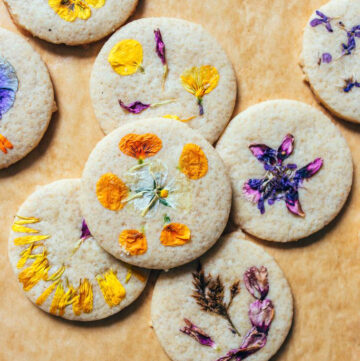 An assortment of flower cookies laid out on brown parchment paper.