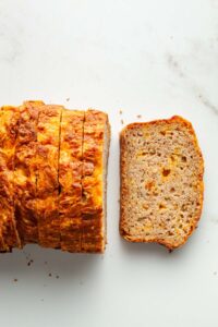 A sliced apple cheddar loaf on a marble surface.