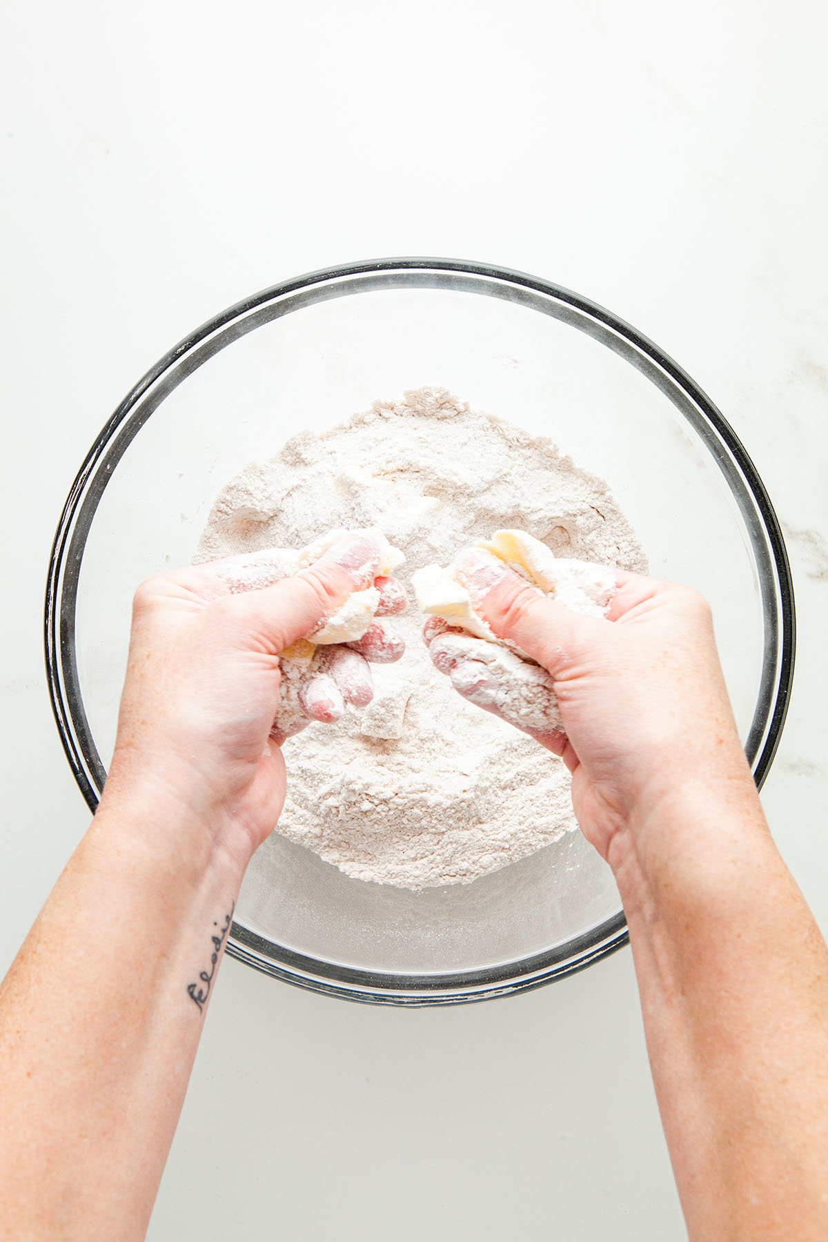 Hands rubbing butter into flour.