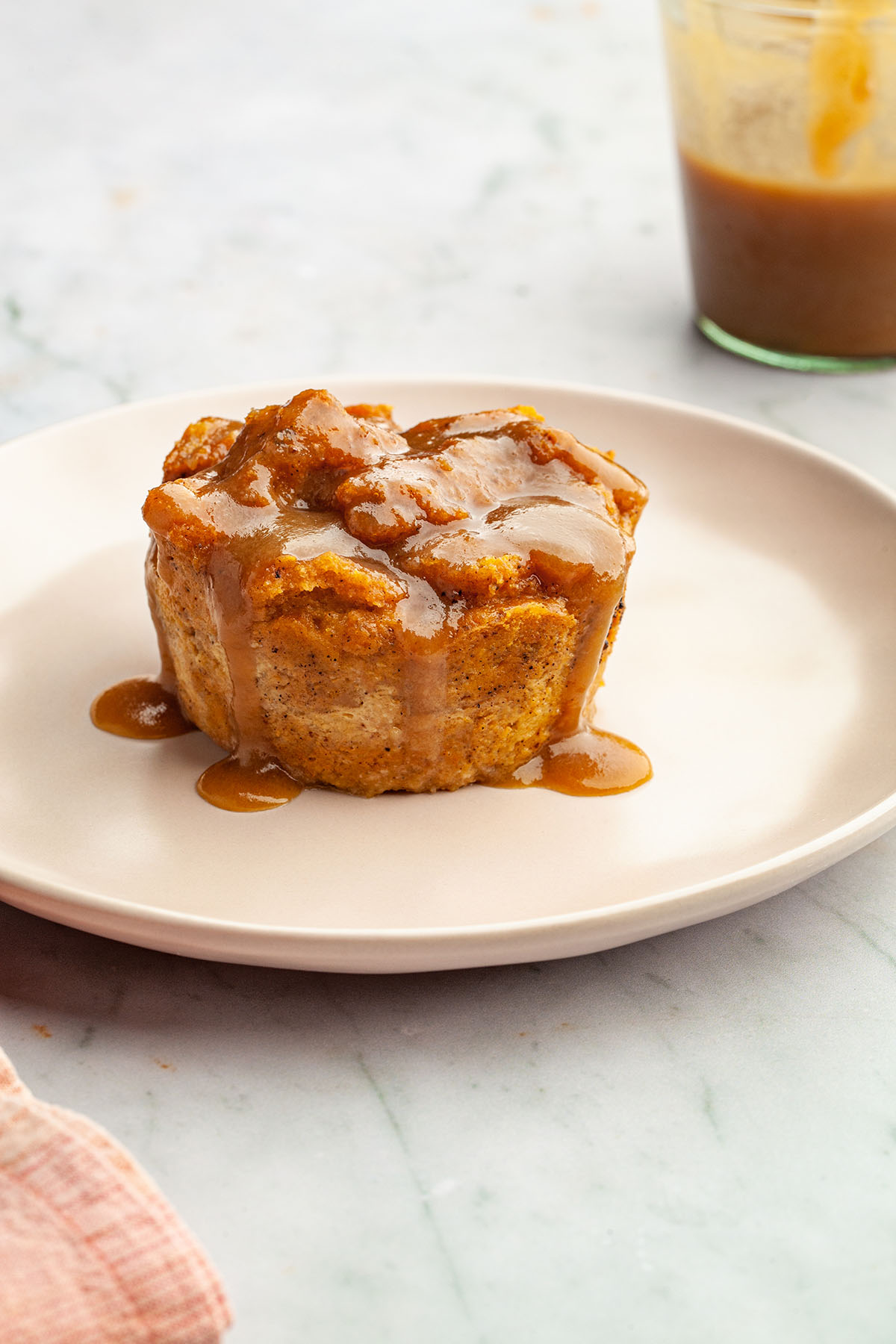 A serving of pumpkin bread pudding on a plate, topped with butterscotch sauce.