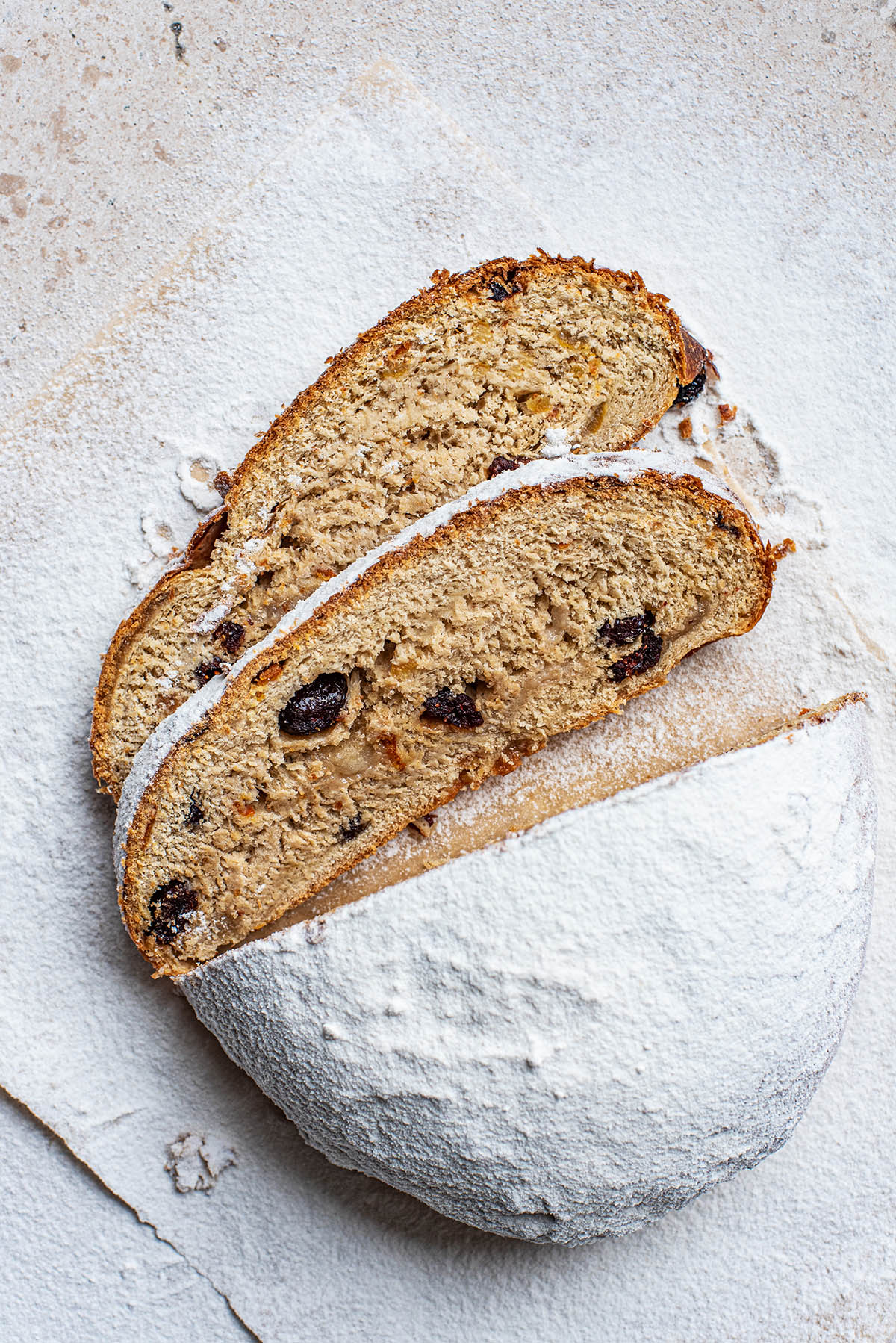 Icing sugar coated stollen with two slices cut.