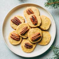Overhead image of a plate of pecan shortbread cookies surrounded by decorative pieces of evergreen.