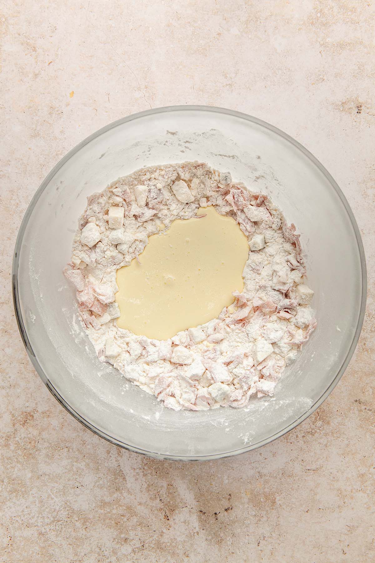 A bowl of dry ingredients with wet ingredients poured into the middle, unmixed.