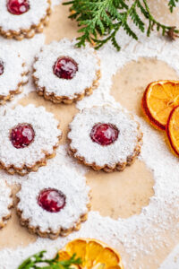 Close up of linzer cookies with dried oranges and greenery.