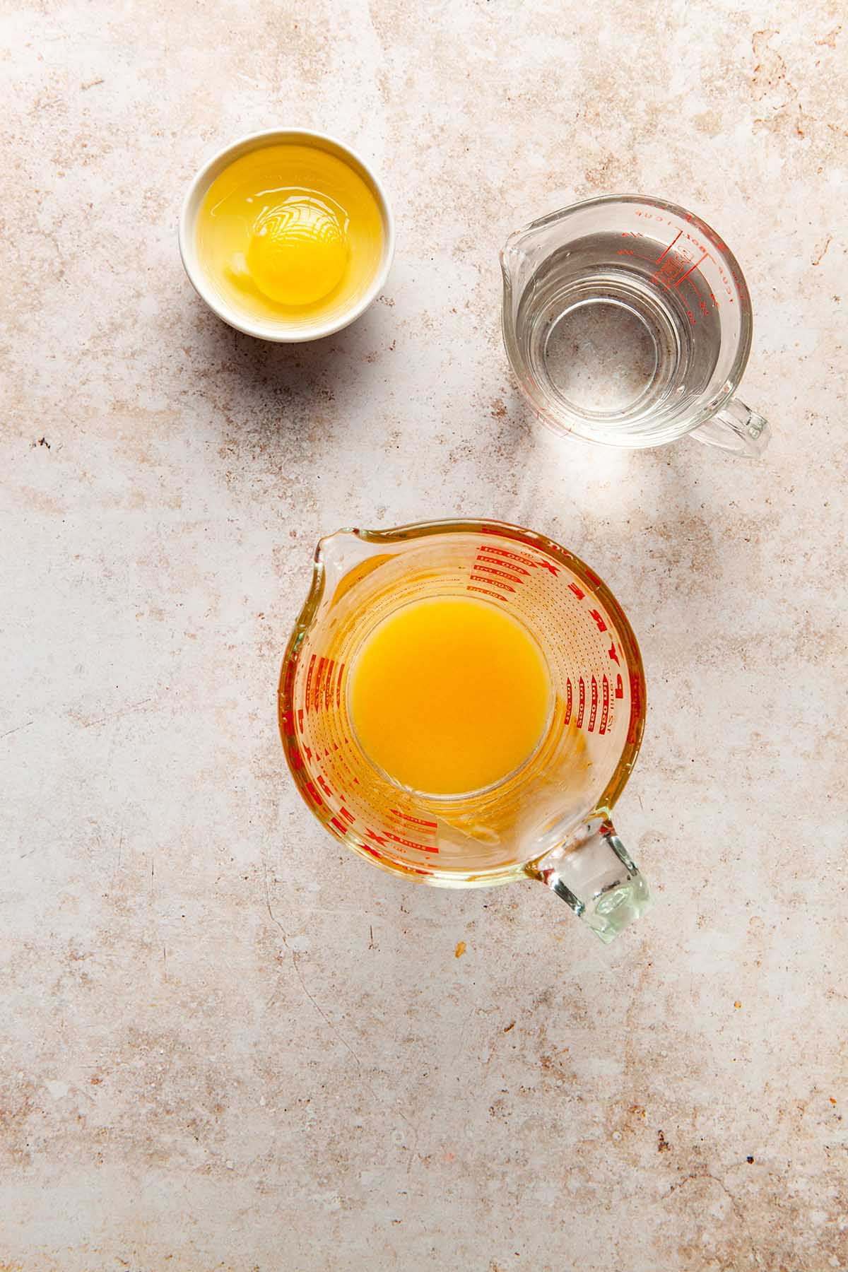 Orange juice, water, and an egg in separate vessels waiting to be mixed together.