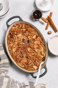 An oval baking dish of vegan baked oatmeal with pears and pecans.
