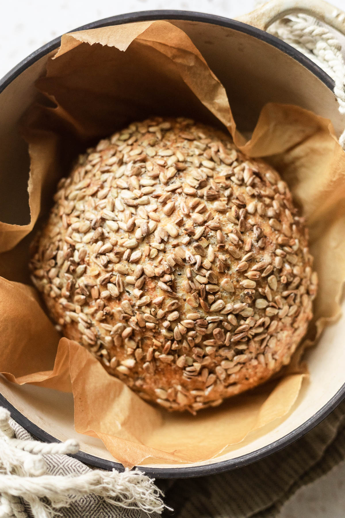 A loaf of sourdough bread in a pot with sunflower seeds.