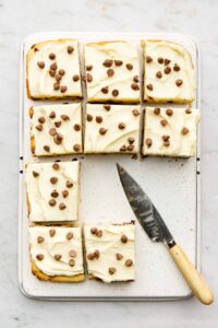 A chocolate chip sheet cake cut into squares on an upsie down baking tray with a knife nearby.