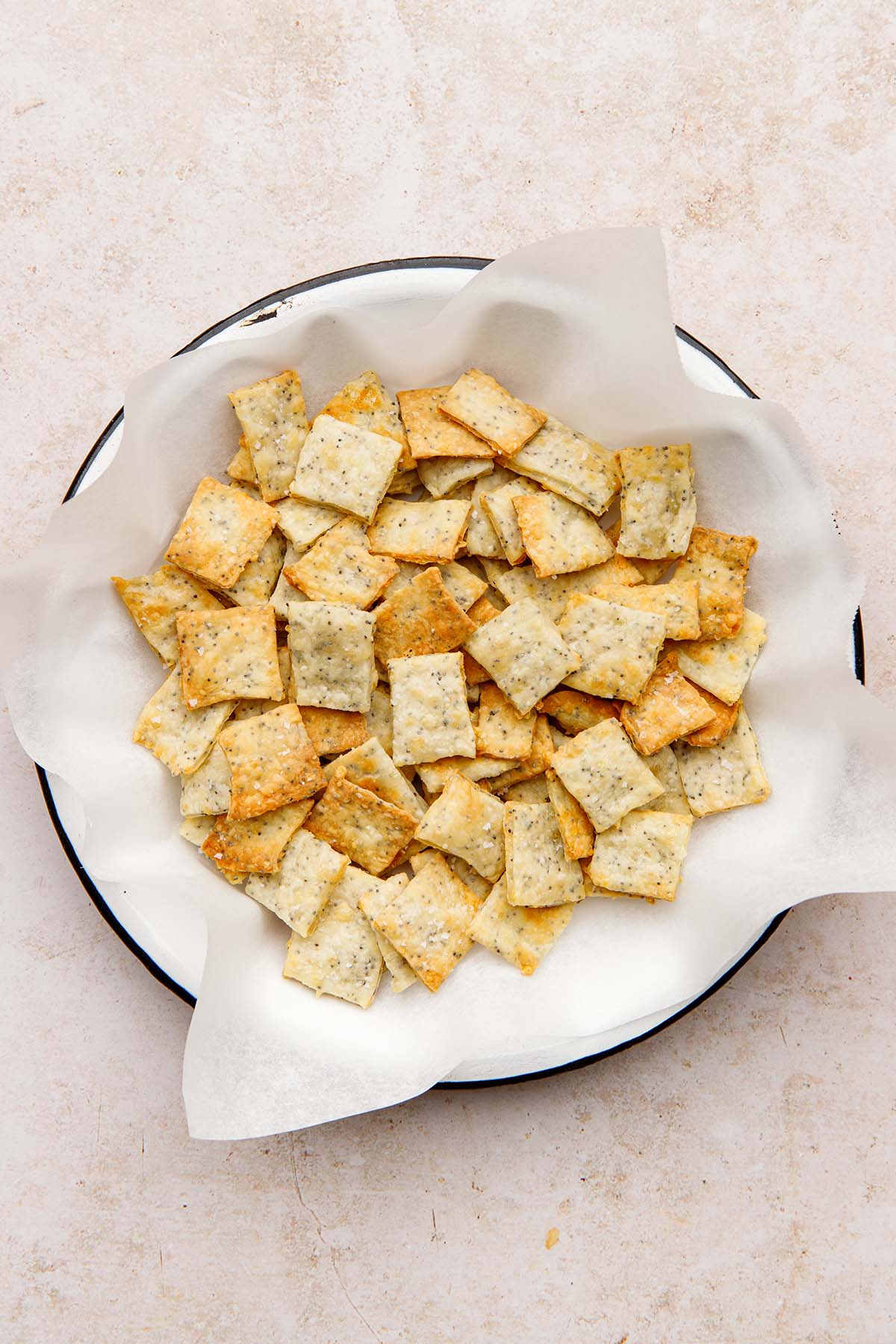 White cheddar crackers in a white dish lined with parchment paper.