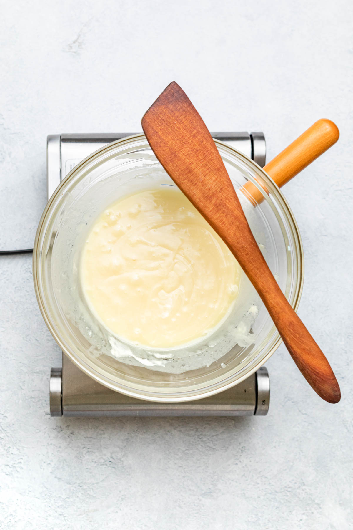 White chocolate and whipping cream heated together in a double boiler on an induction stove.