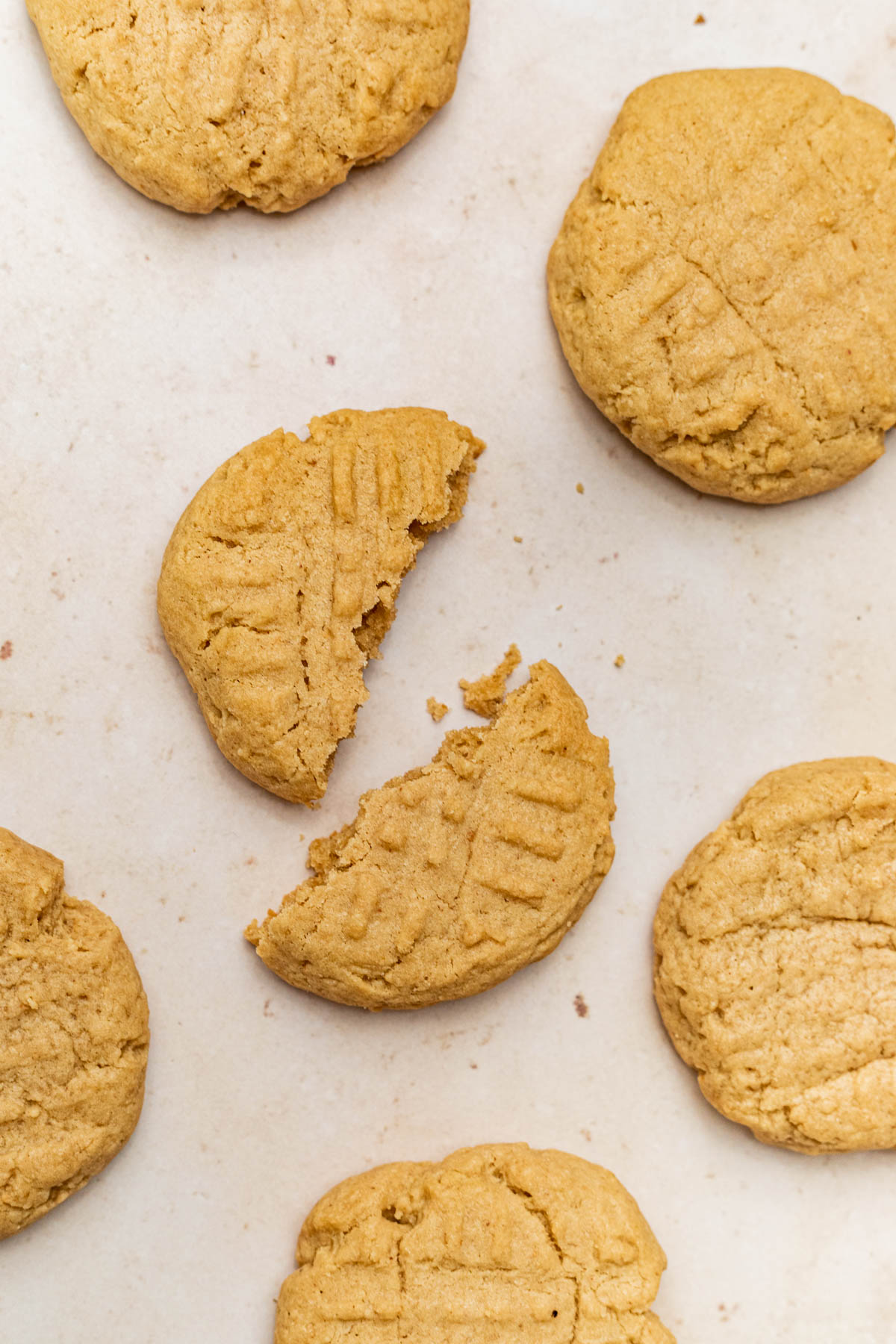 Cookies on a baking sheet, one broken in half.