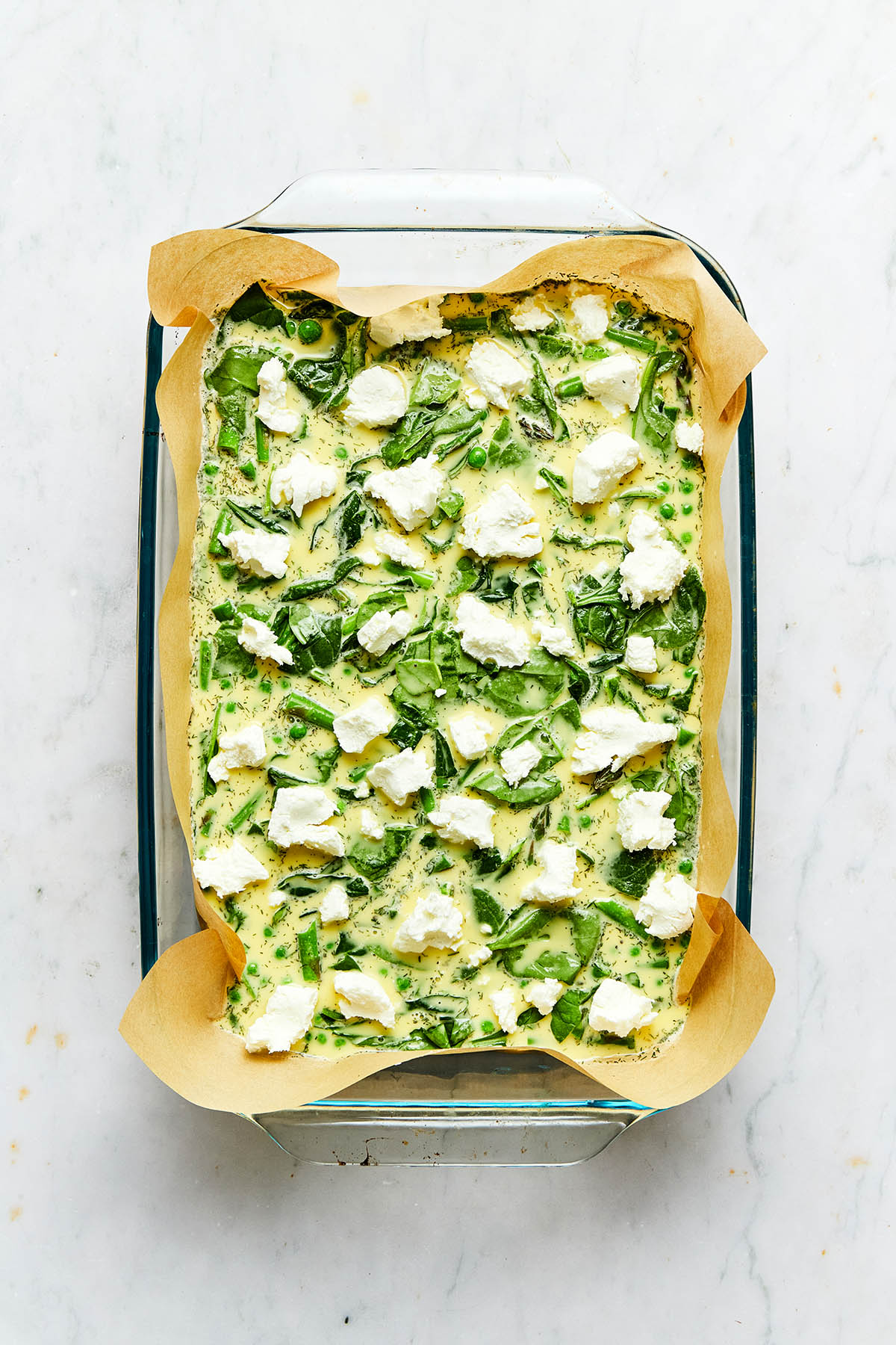 An unbaked egg casserole topped with chunks of soft goat cheese.