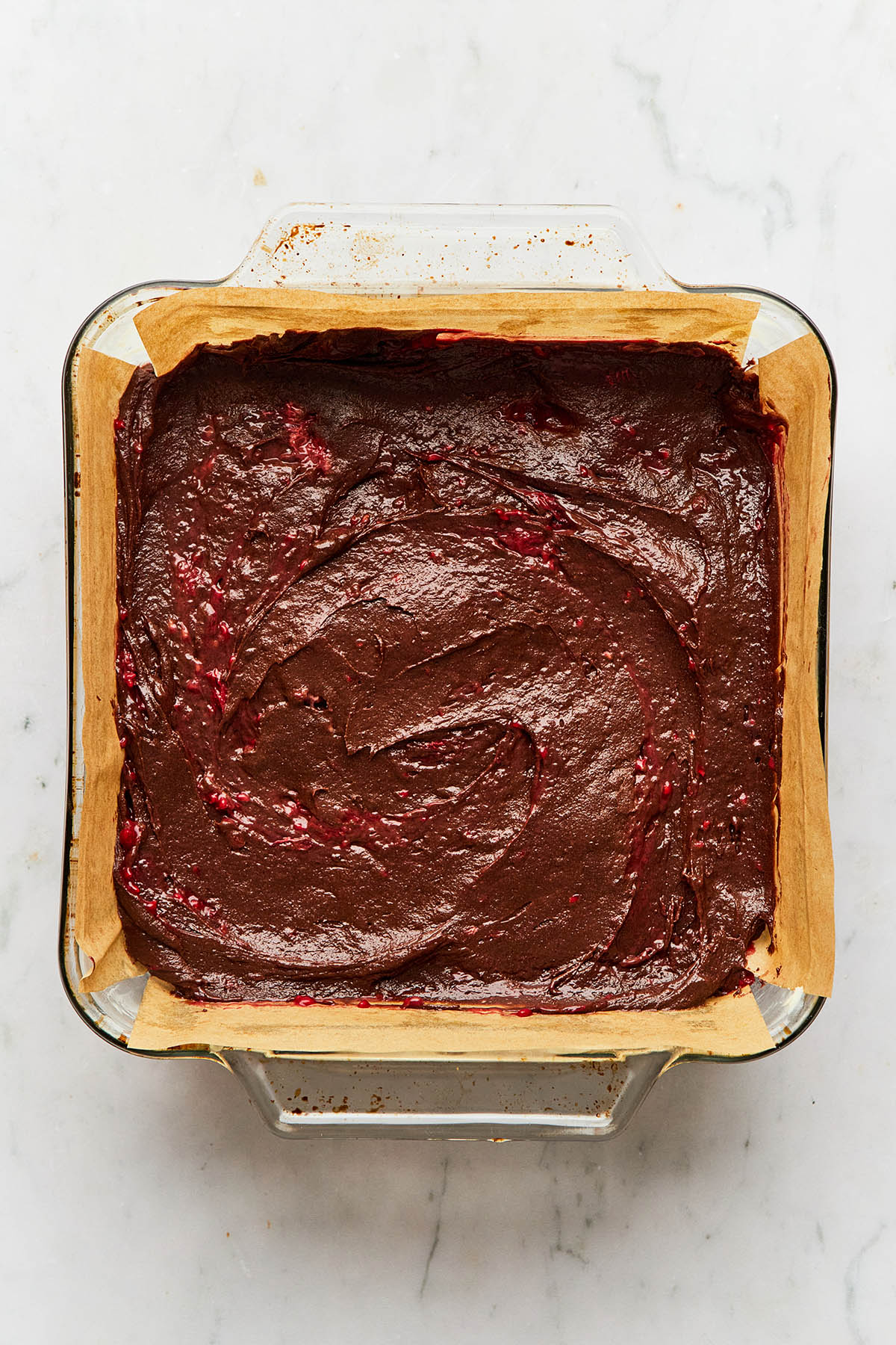 Chocolate batter in a parchment-lined square baking dish.