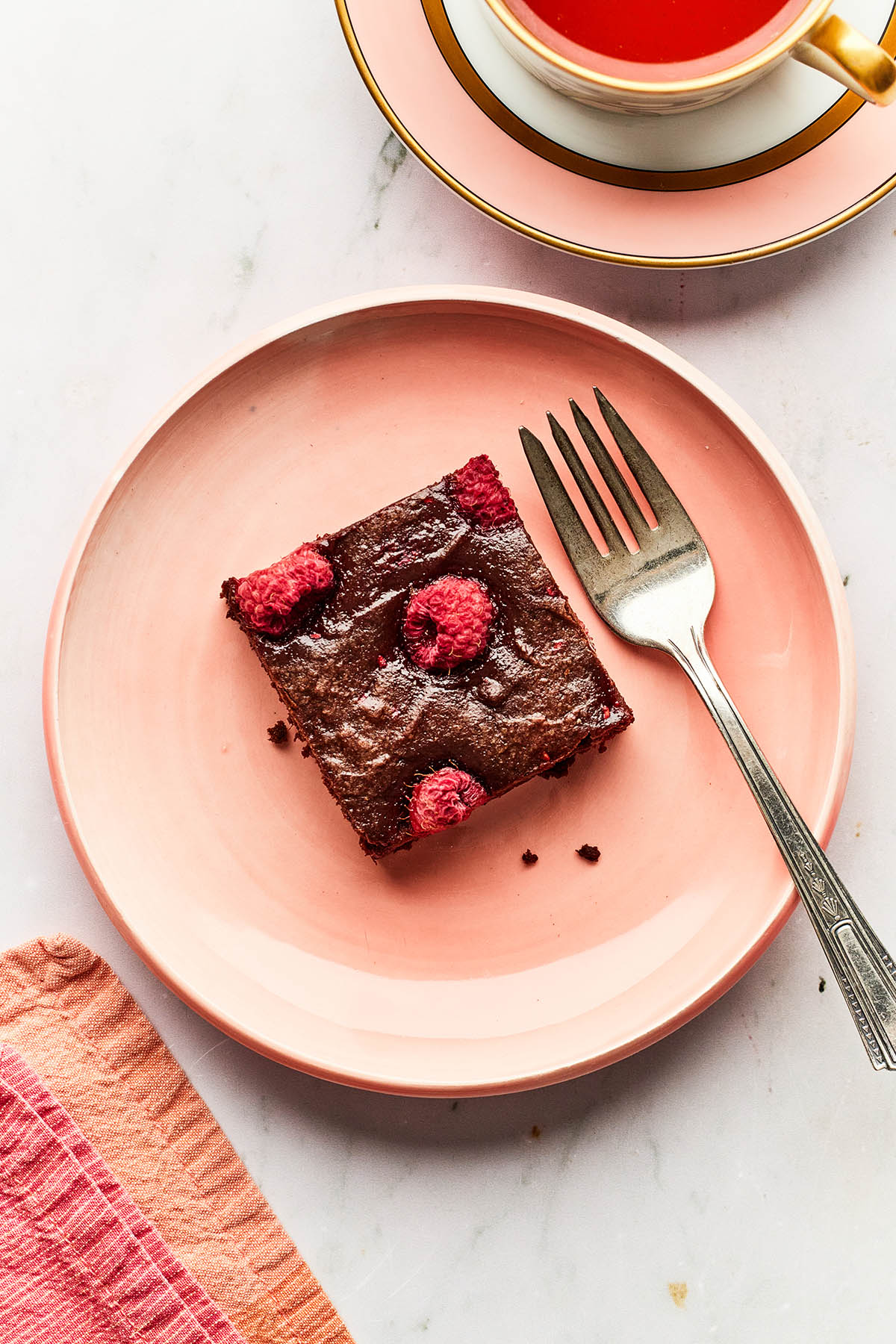 Oberhead image of one raspberry brownie on a pink plate with a fork.