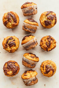 Banana Nutella muffins on a warm-coloured marble surface.