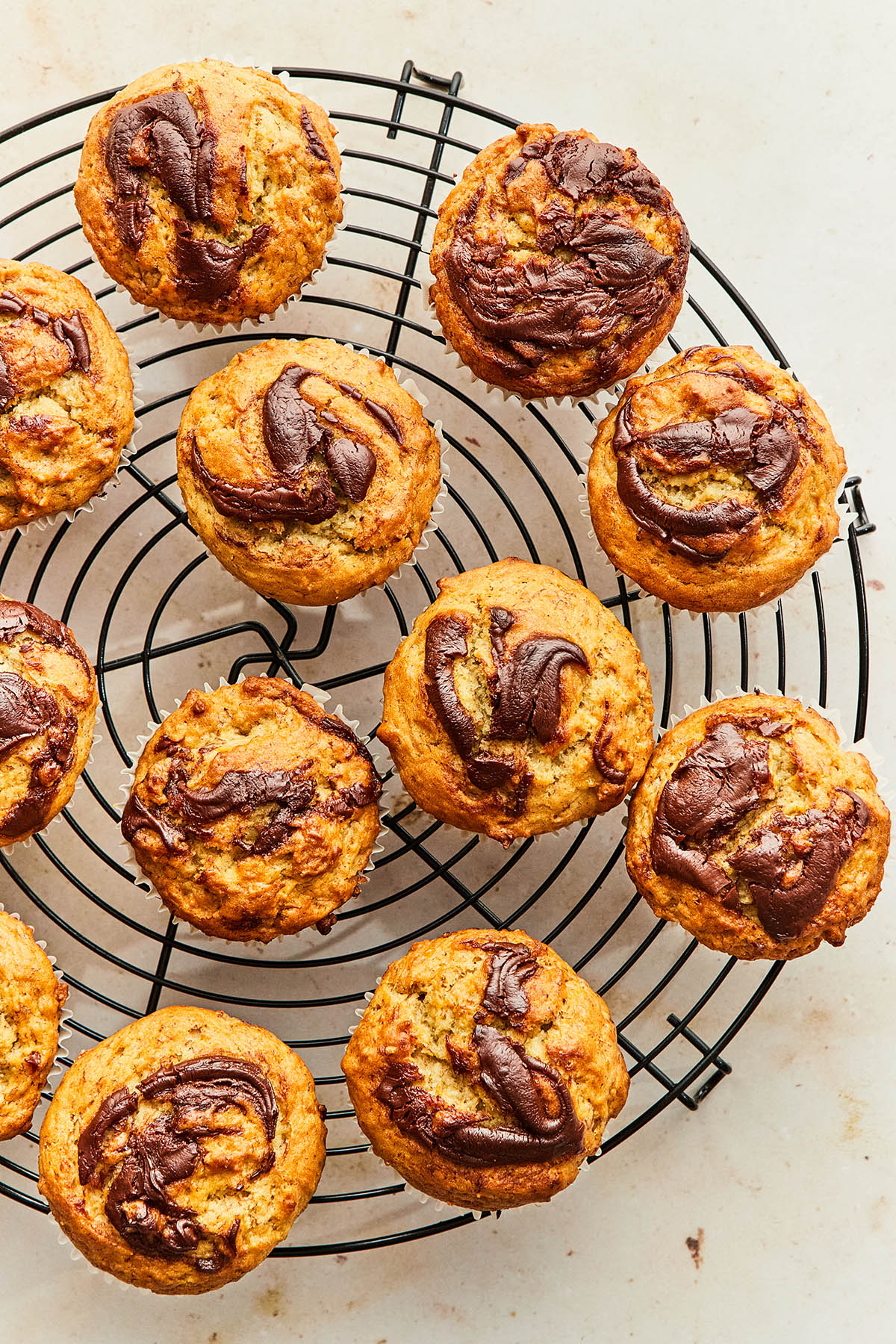 Banana Nutella muffins on a round black wire cooling rack.