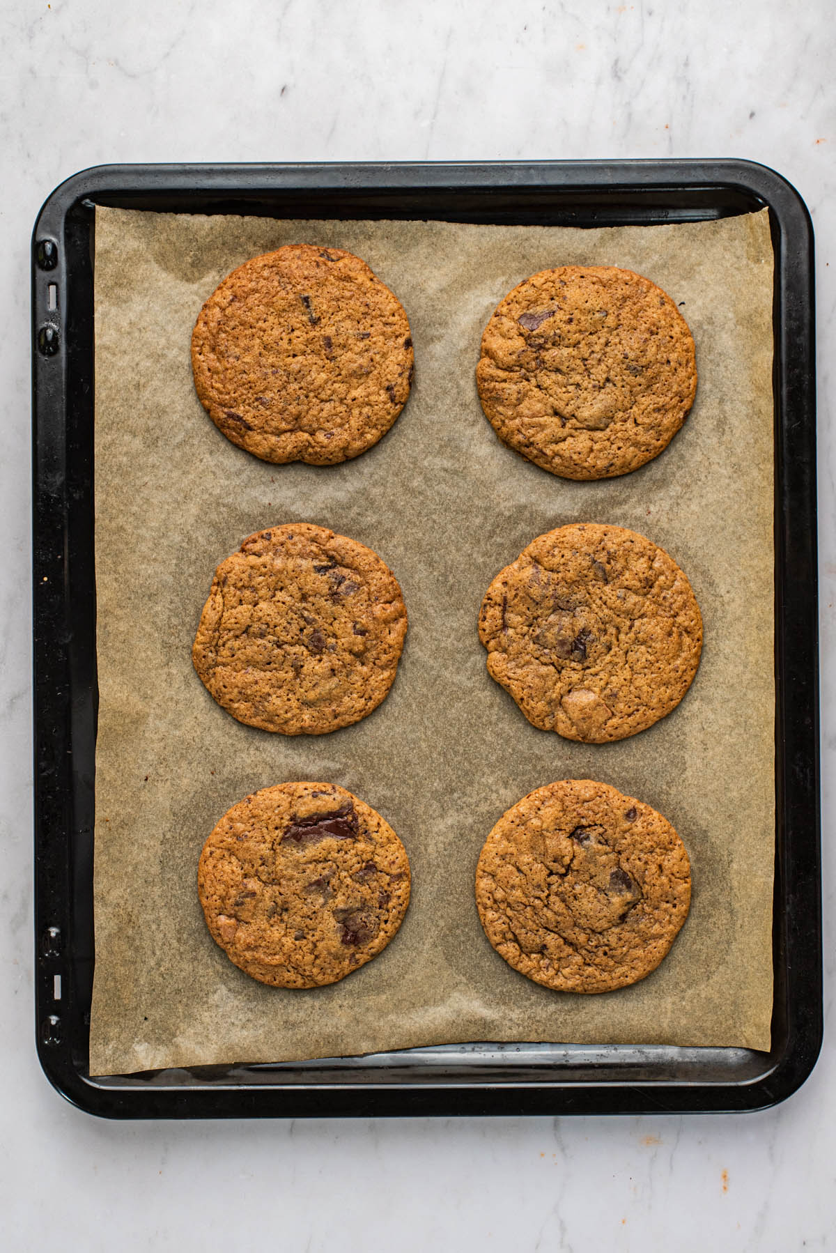 Six large cookies on a baking sheet, baked.