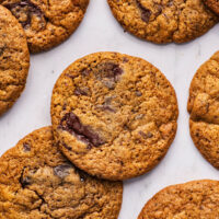 Several chocolate chunk cookies on a pale marble background.