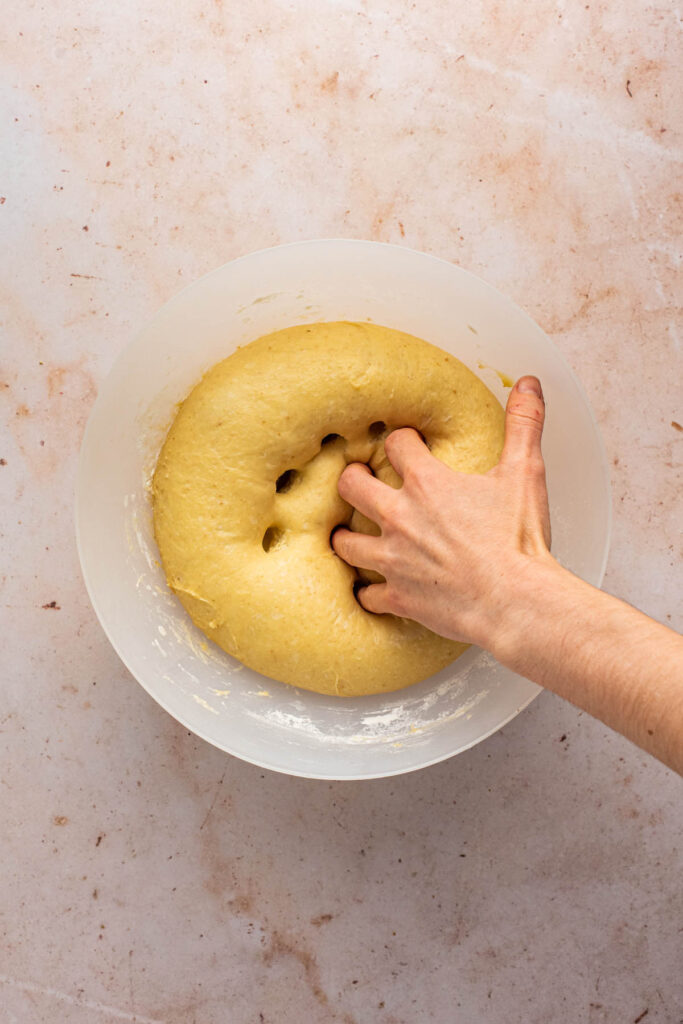 Hand poking into the dough to deflate it.