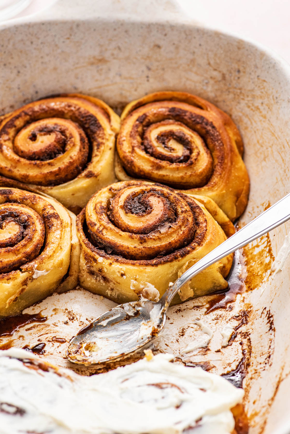 Two cinnamon rolls with a touch of frosting in a deep plate.