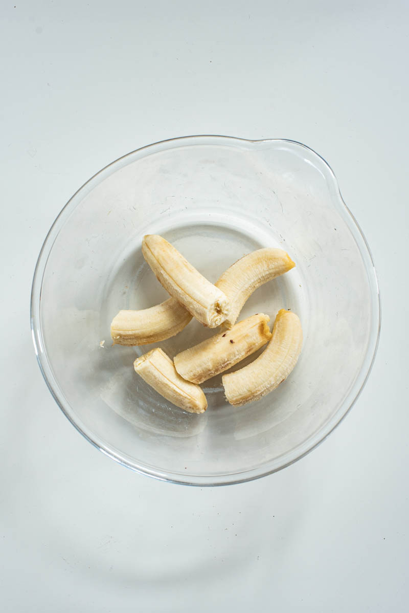 Bananas, peeled, in a large glass mixing bowl.