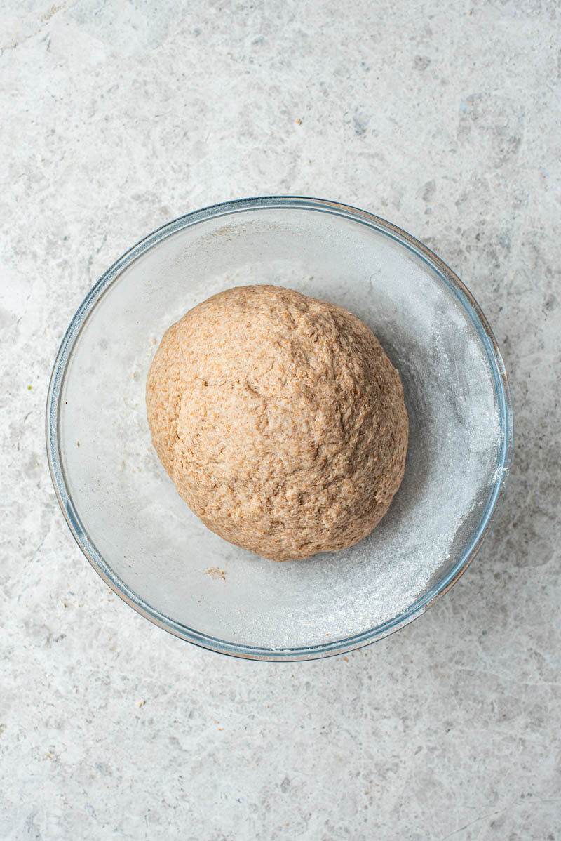 Bagel dough placed back into the glass bowl after kneading.