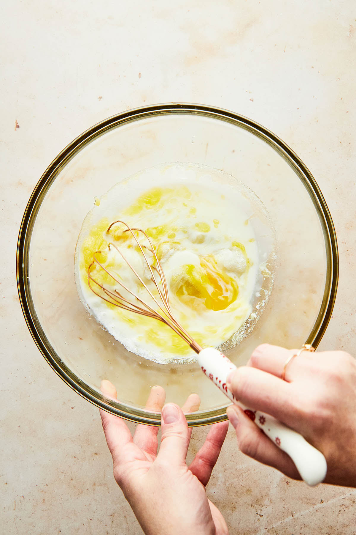 A hand using a whisk to mix wet ingredients together.