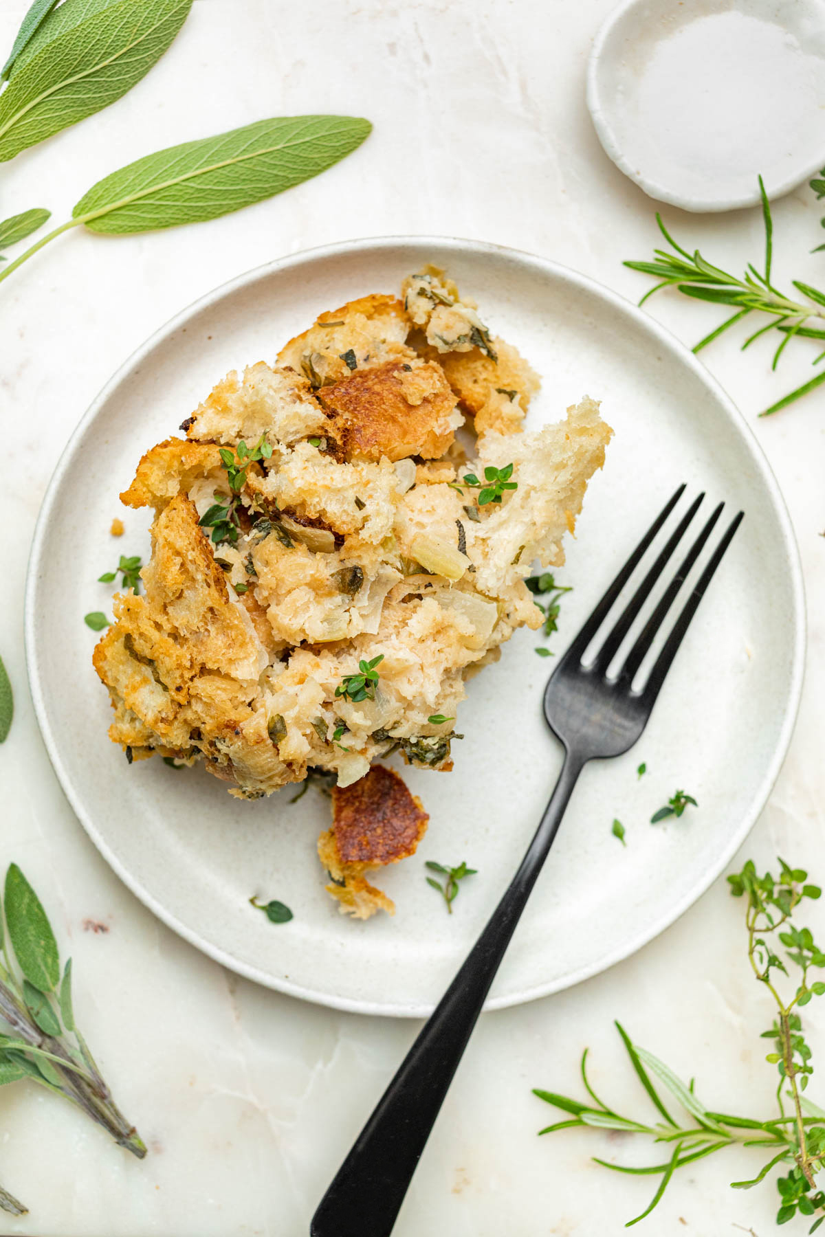 Sourdough stuffing on a small plate with a fork and herbs.