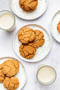 Several spice cookies arranged on small plates with milk in glasses.