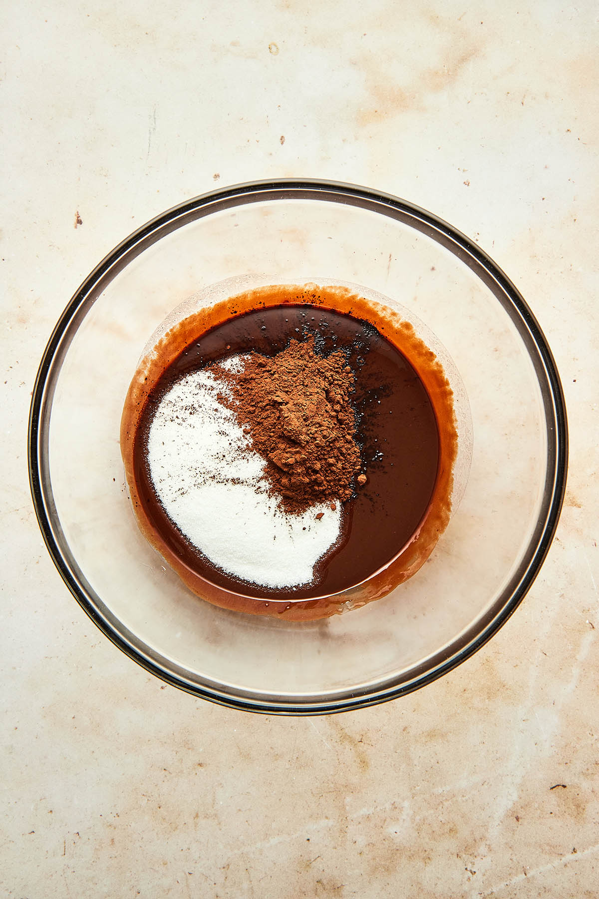 Melted chocolate, sugar, and cocoa in a large glass mixing bowl.