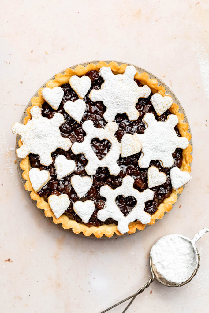 Mince pie topped with icing sugar dusted pastry shapes.