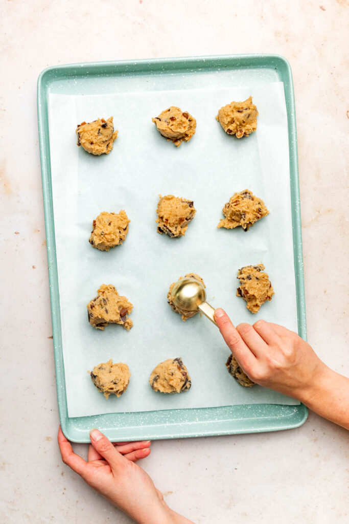 Dropping scoops of cookie dough onto a baking sheet.