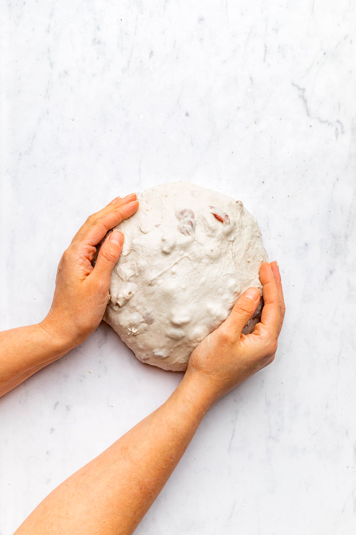 Hands shaping dough into a round shape.