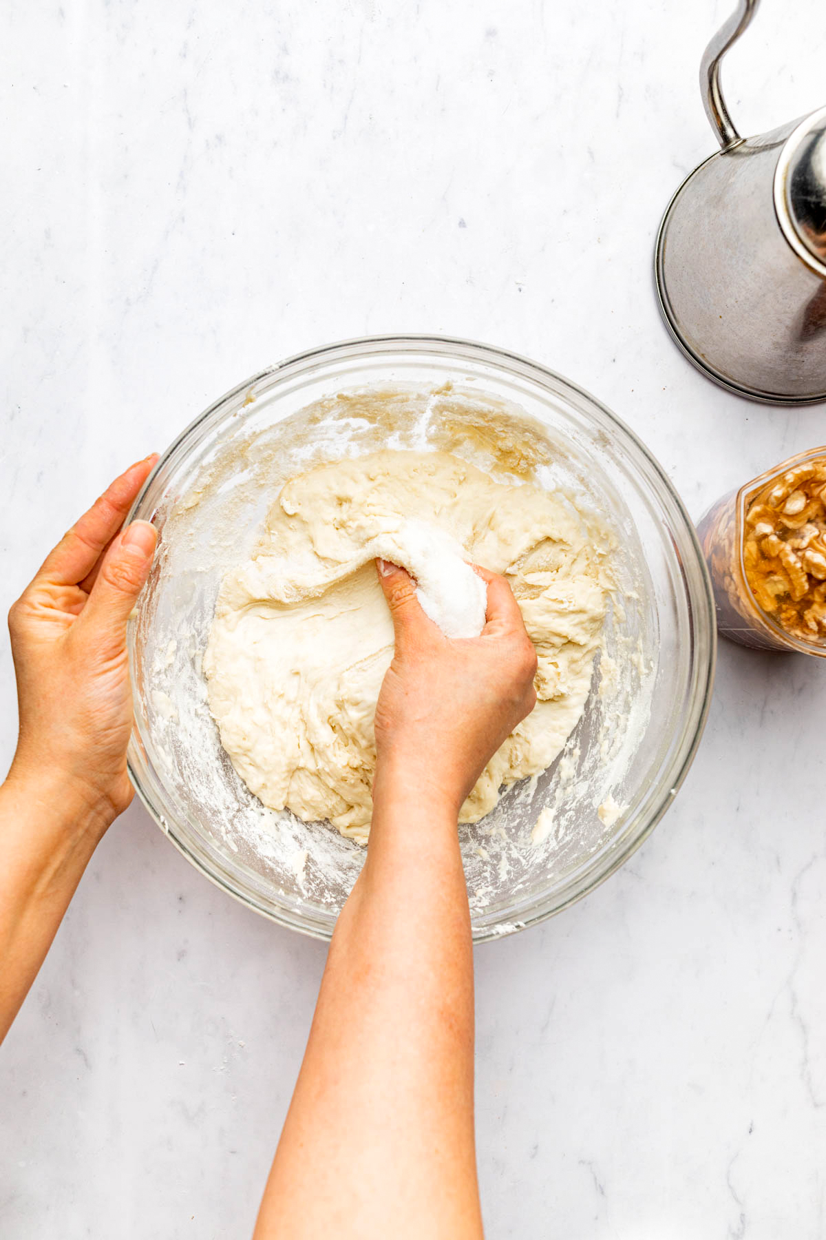 A hand reaching into a bowl of dough.