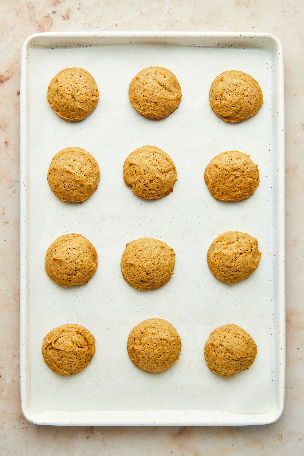 Overhead image of cookies on a white baking sheet lined with parchment paper.