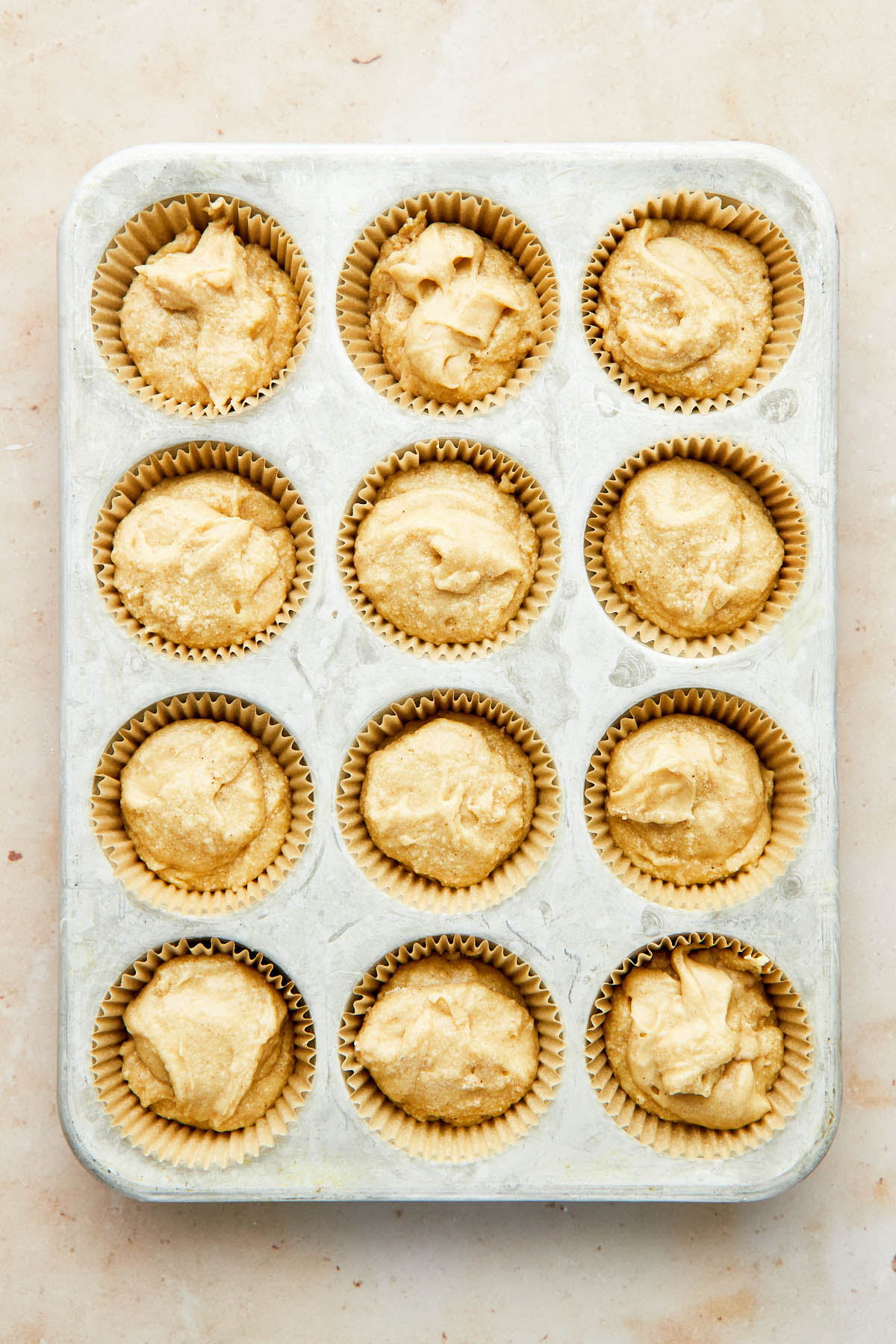 A muffin tin filled with paper wrapper and batter.