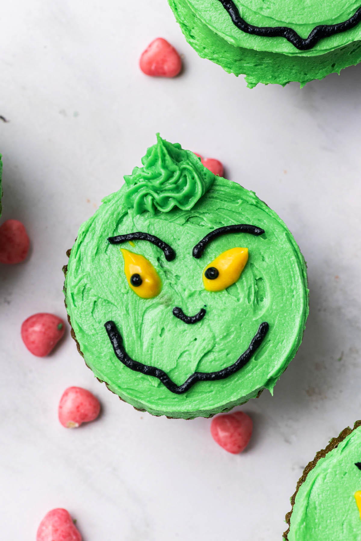 Closer image of a green-iced cupcake with frosting piped to look like the grinch.