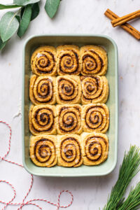 Cinnamon rolls in a rectangular baking dish, with a drizzle of glaze.