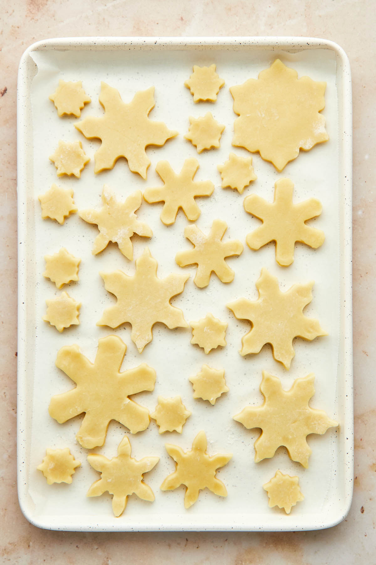 A pan of unbaked snowflake sugar cookies.