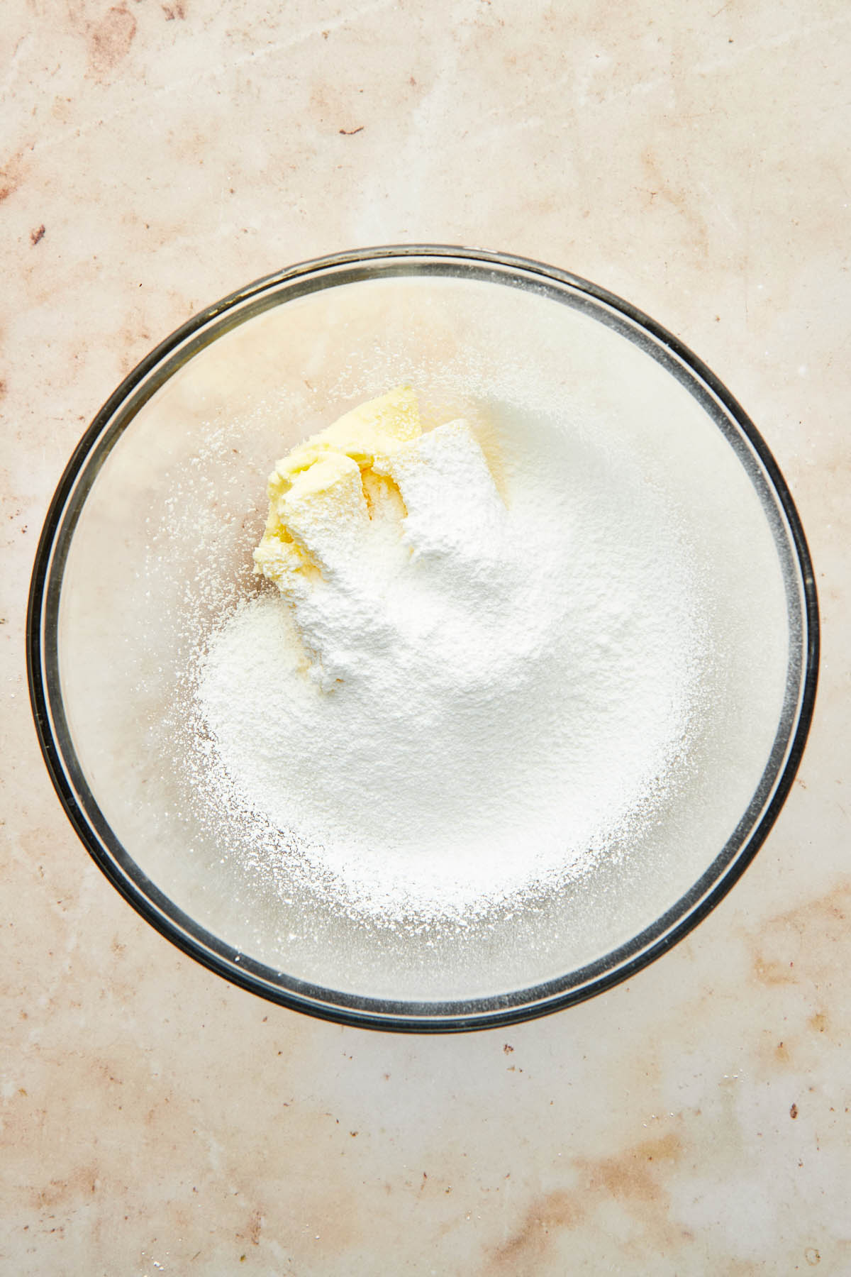 A bowl of butter and sugar with powdered sugar sifted on top.