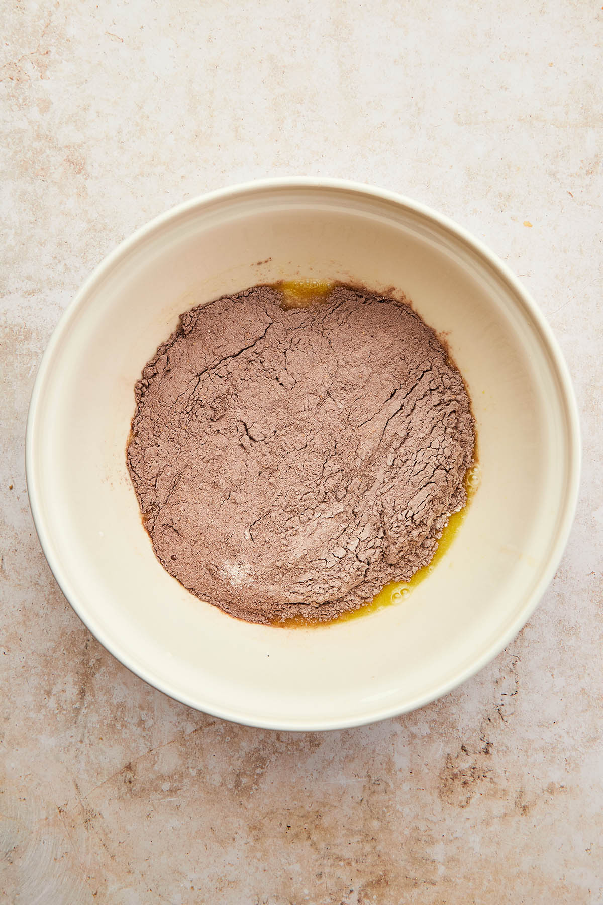 A bowl of unmixed wet and dry cake ingredients.